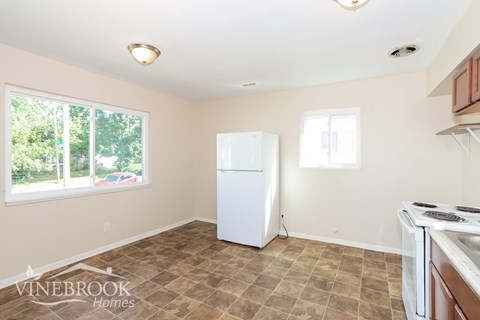A kitchen with a white refrigerator and a tiled floor.