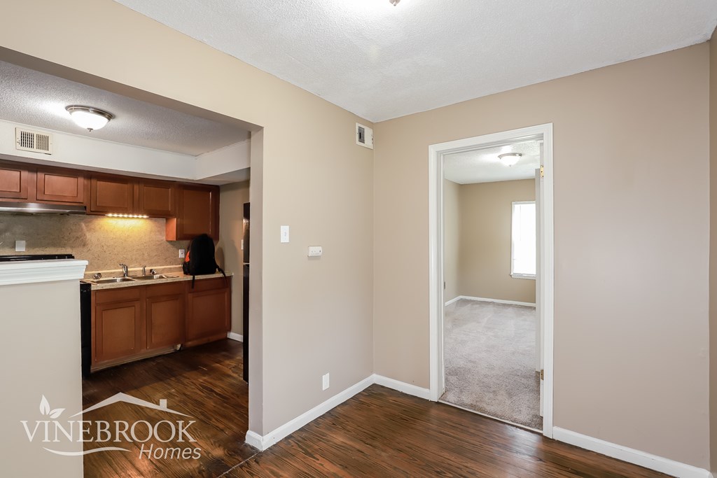 A room with a carpeted hallway leading to a bathroom.