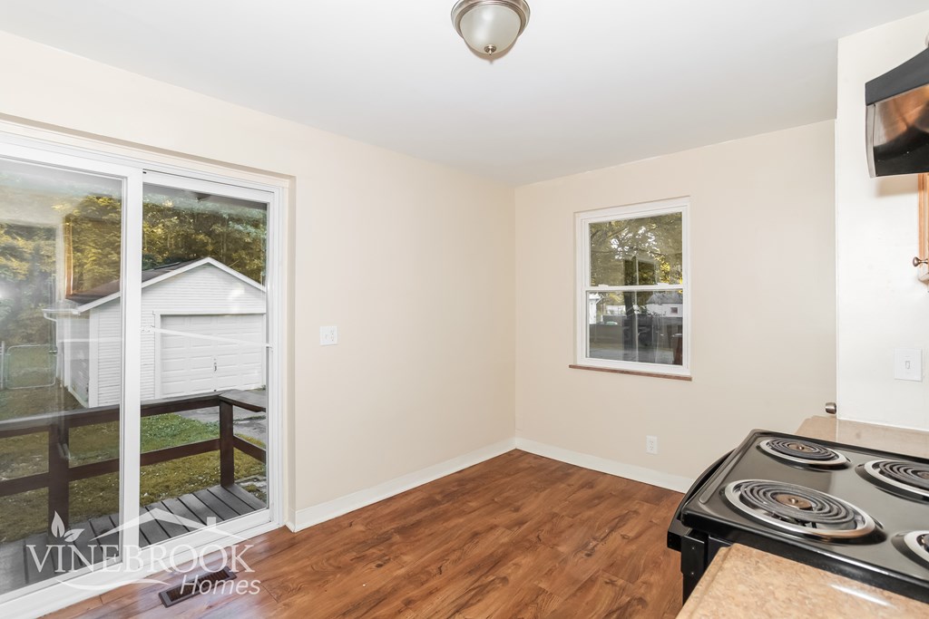 A room with a stove top oven and a window overlooking a house.