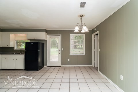 A kitchen with a black fridge and white cabinets.