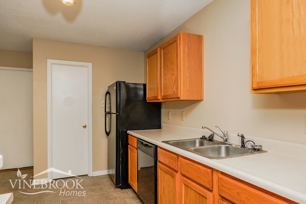 A kitchen with wooden cabinets and a black refrigerator.