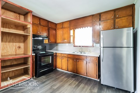 A kitchen with wooden cabinets and a stainless steel refrigerator.