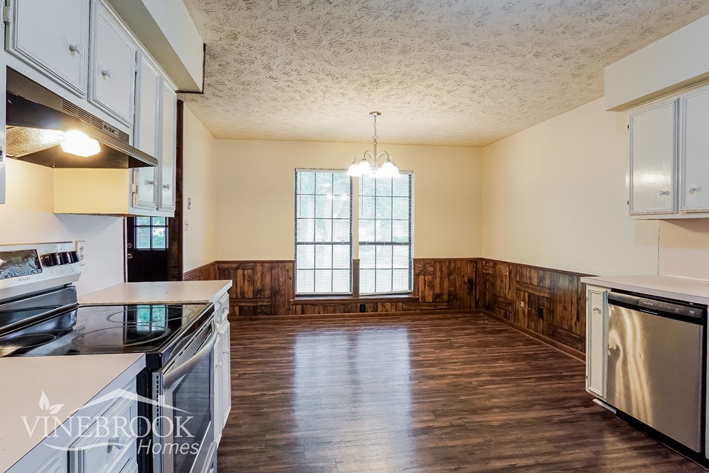 an empty kitchen with wood flooring and a large window