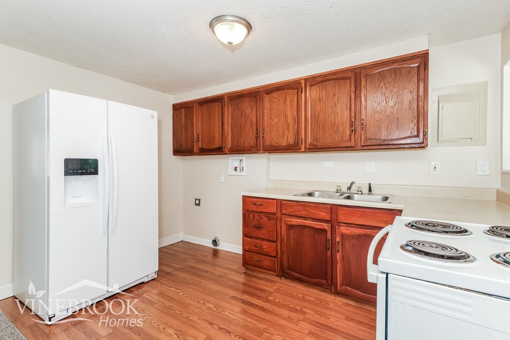 a kitchen with wooden cabinets and a white stove and refrigerator