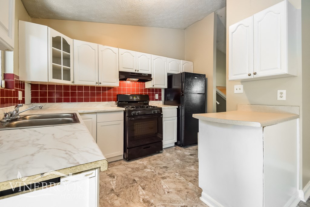 a kitchen with white cabinets and black appliances