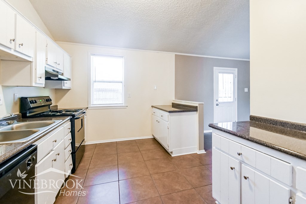 a kitchen with white cabinets and a stove and a sink