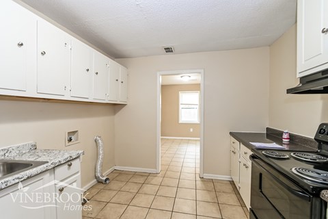 A kitchen with white cabinets and a black stove top oven.
