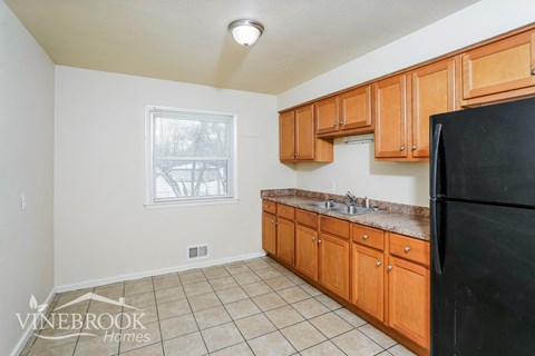 A kitchen with wooden cabinets and a black refrigerator.