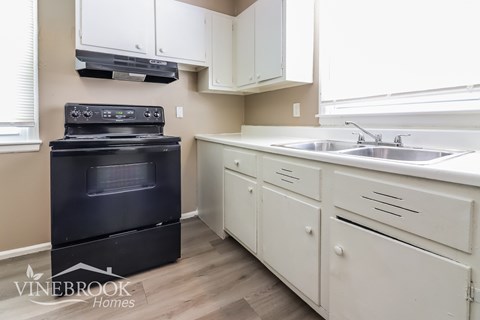 A black oven is in a kitchen with white cabinets.