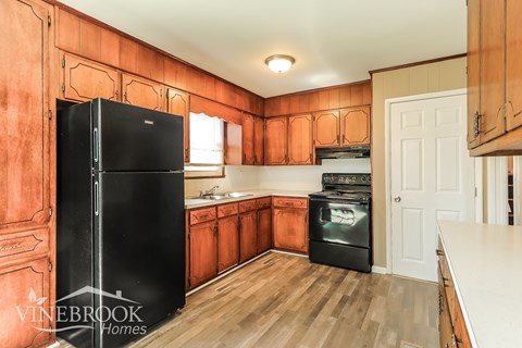A kitchen with wooden cabinets and a black refrigerator.