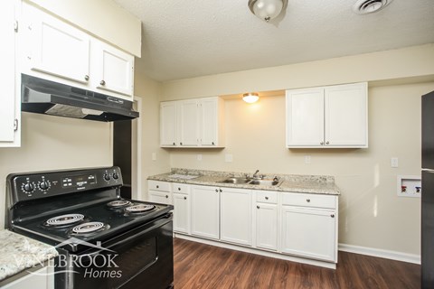 A kitchen with a black stove top oven and white cabinets.