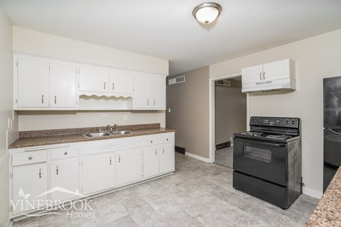 A kitchen with white cabinets and a black stove top oven.