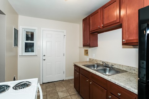 A kitchen with brown cabinets and a black fridge.