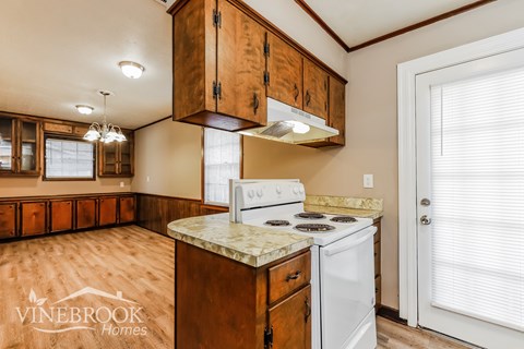 A kitchen with wooden cabinets and a white stove top oven.