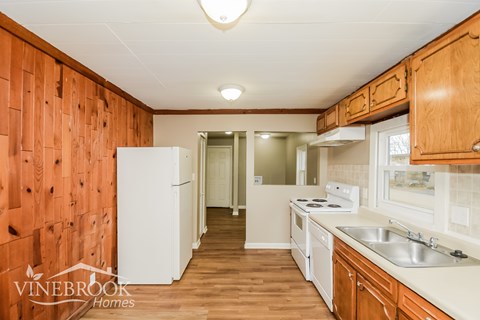 A kitchen with wooden cabinets and a white fridge.