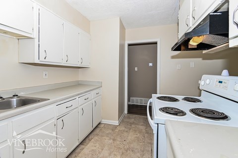 A kitchen with white cabinets and a stove top oven.