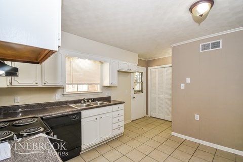 A kitchen with a black stove top oven and white cabinets.