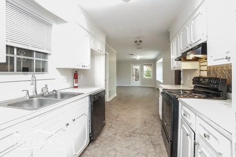 A kitchen with white cabinets and appliances.