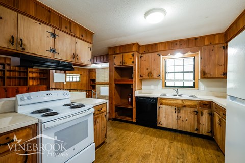 A kitchen with wooden cabinets and a white stove top oven.