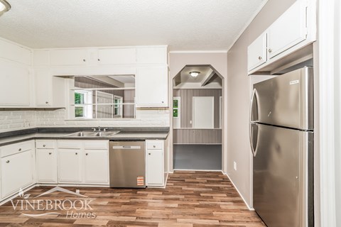 A kitchen with white cabinets and a wooden floor.