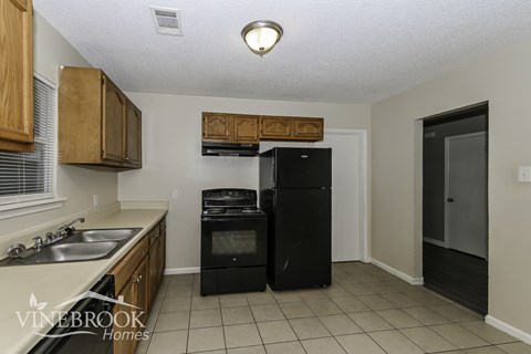 A kitchen with a black fridge and a black dishwasher.