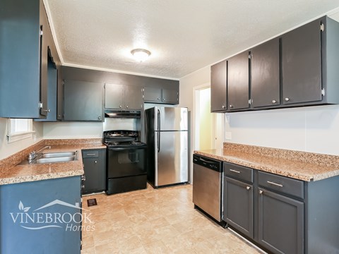 A kitchen with a Vinebrook Homes sign on the island.