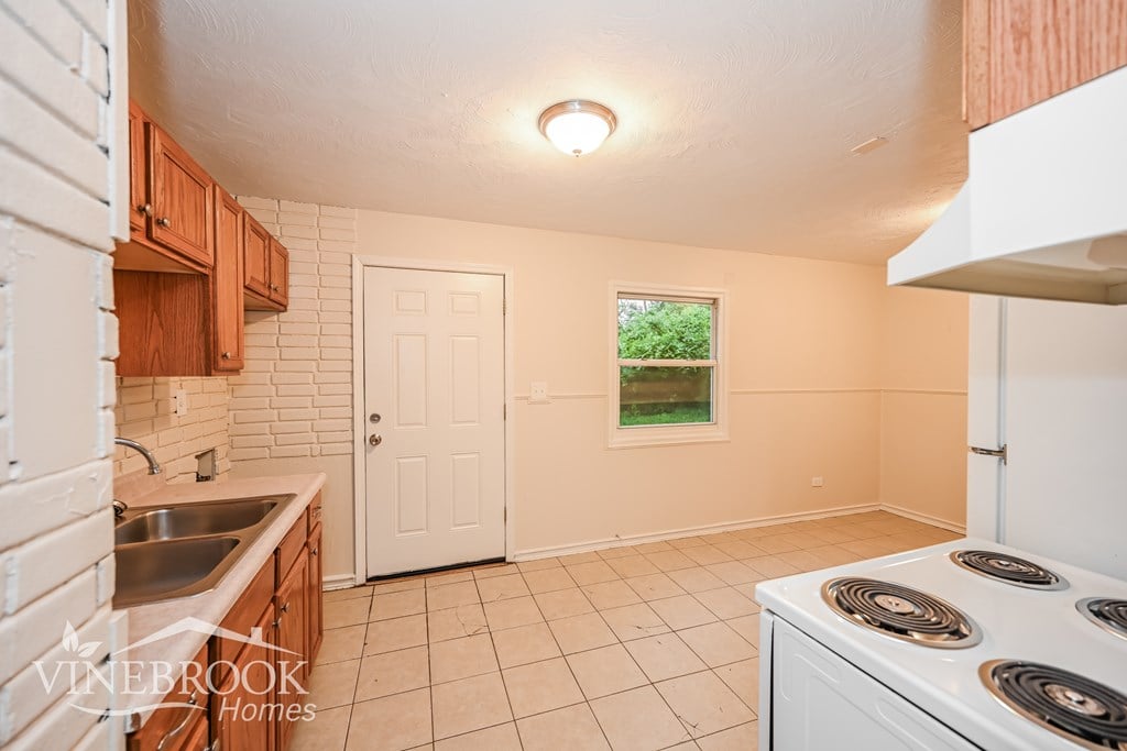 A kitchen with a stove top oven and a window.