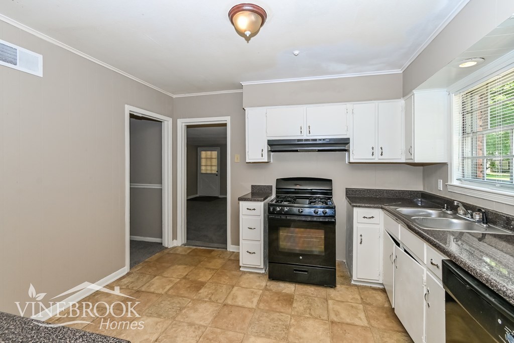 A kitchen with a black oven and white cabinets.