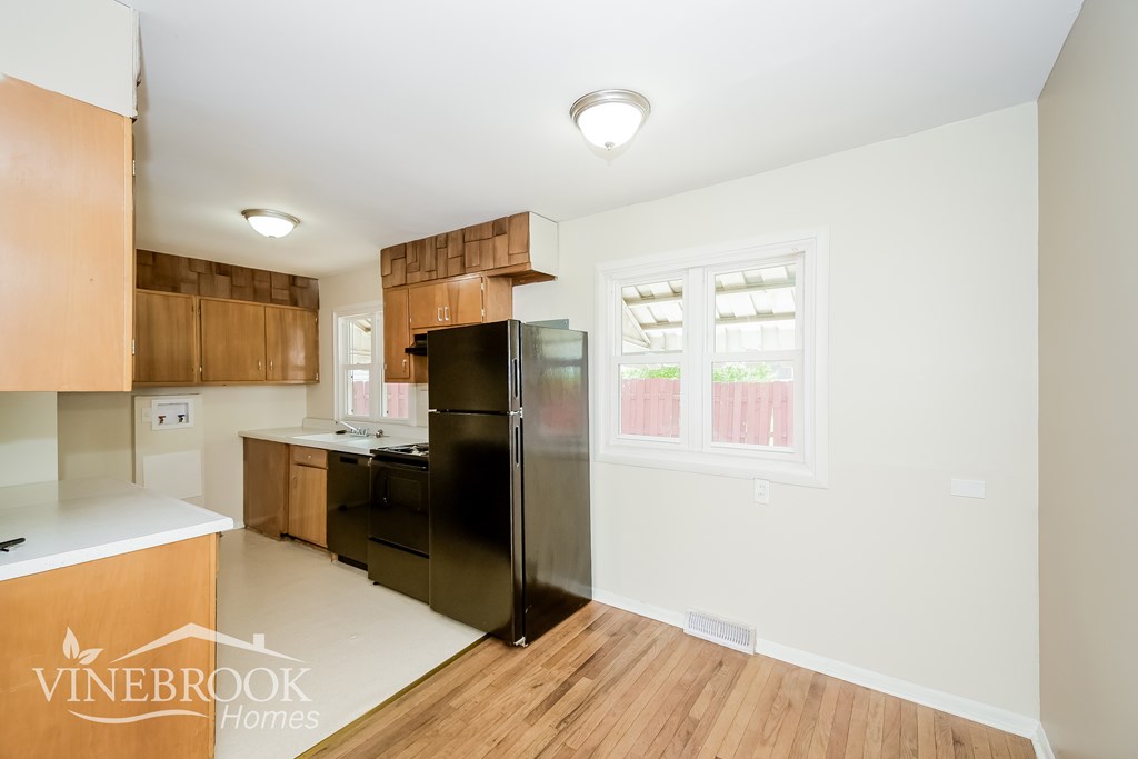 A kitchen with wooden cabinets and a black refrigerator.