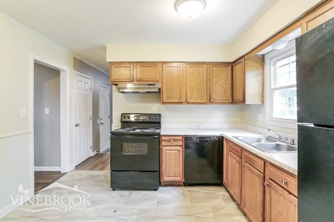 A kitchen with wooden cabinets and black appliances.