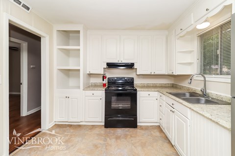 A kitchen with a black stove top oven and white cabinets.