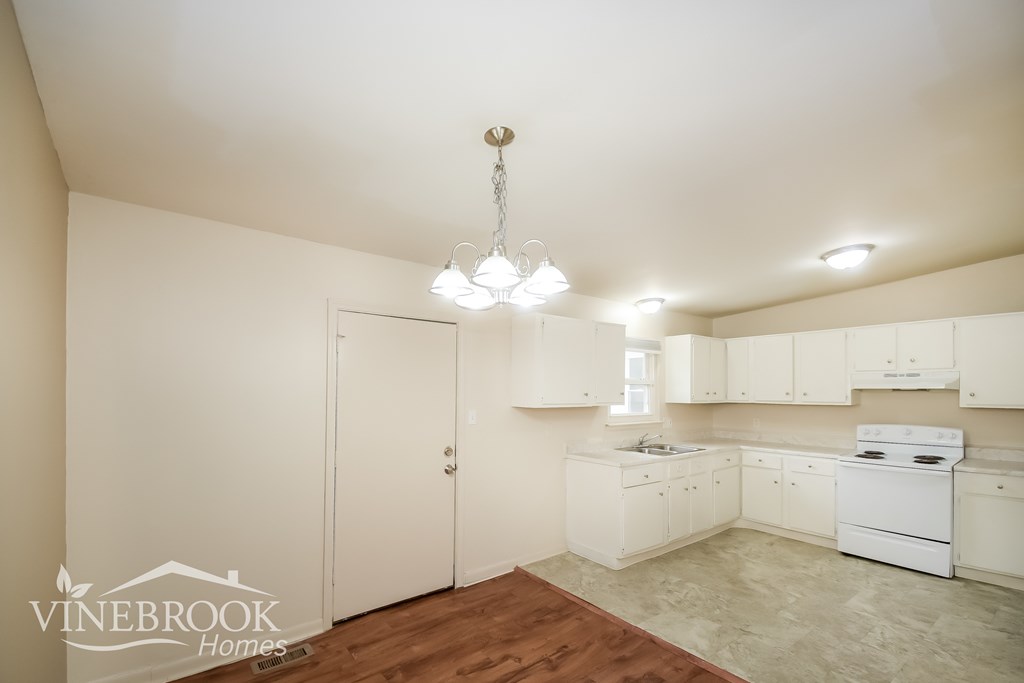 A kitchen with white cabinets and a wooden floor.