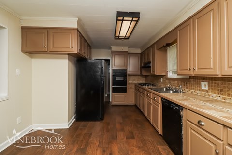 A kitchen with wooden cabinets and black appliances.