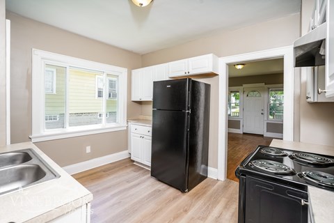 A kitchen with a black refrigerator and stove top oven.