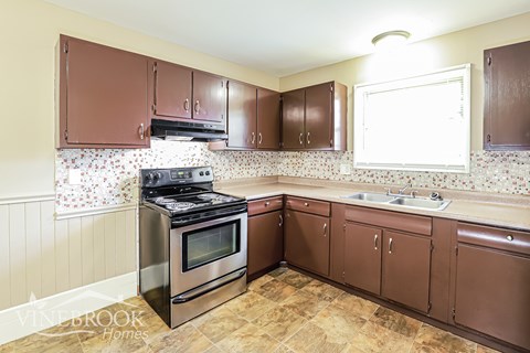 A kitchen with brown cabinets and a stove top oven.
