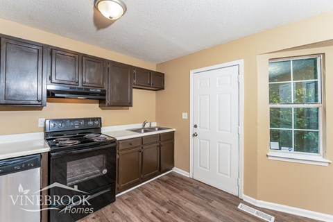 A kitchen with a black stove top oven and a white door.