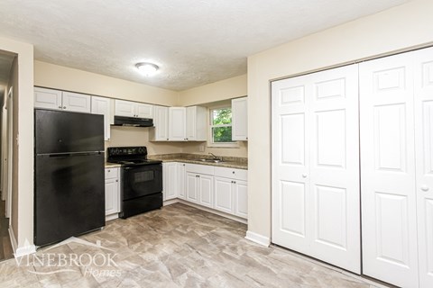 A kitchen with white cabinets and a black fridge.