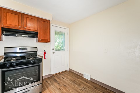 A kitchen with a stove top oven and wooden cabinets.