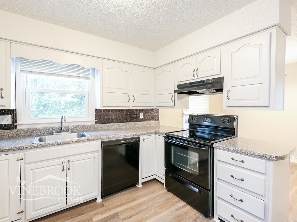 A kitchen with black appliances and white cabinets.