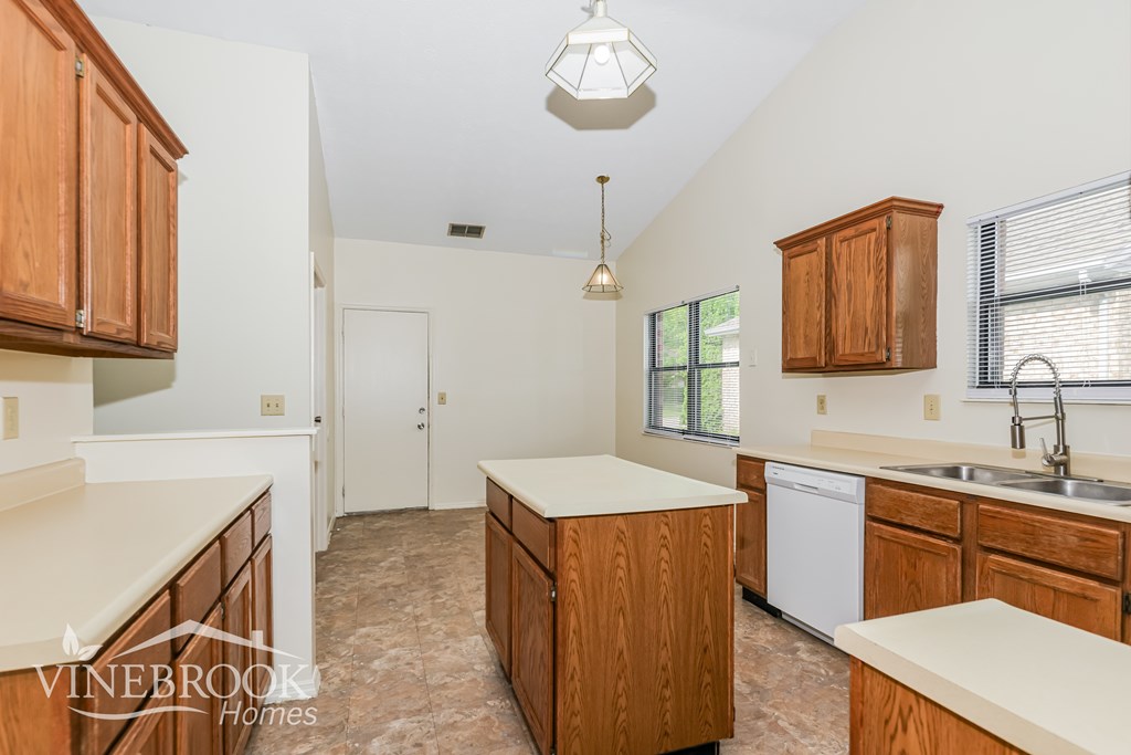 A kitchen with wooden cabinets and a white dishwasher.