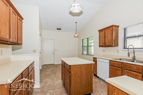 A kitchen with wooden cabinets and a white dishwasher.