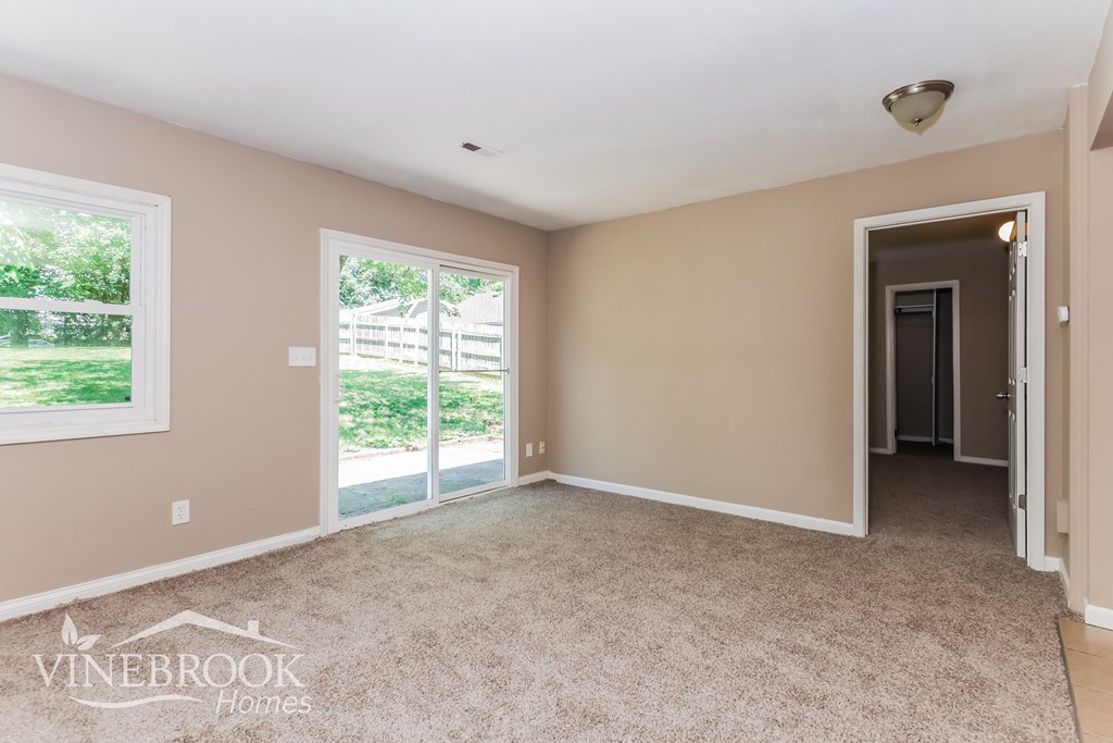 an empty living room with a door to a hallway and a window
