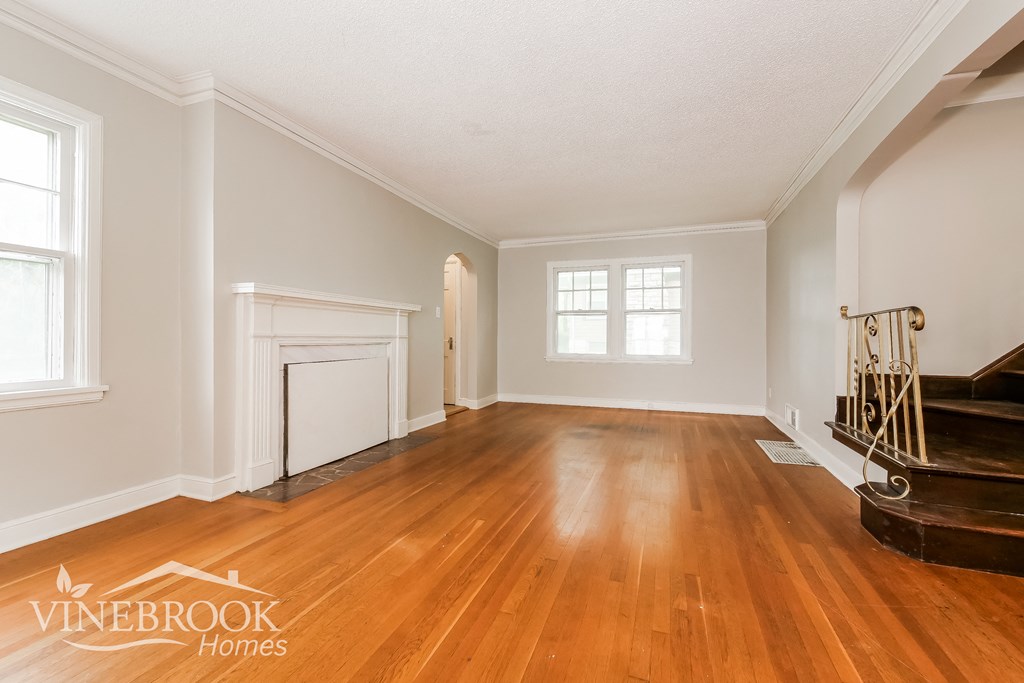 the living room and dining room of a home with wood floors and a fireplace