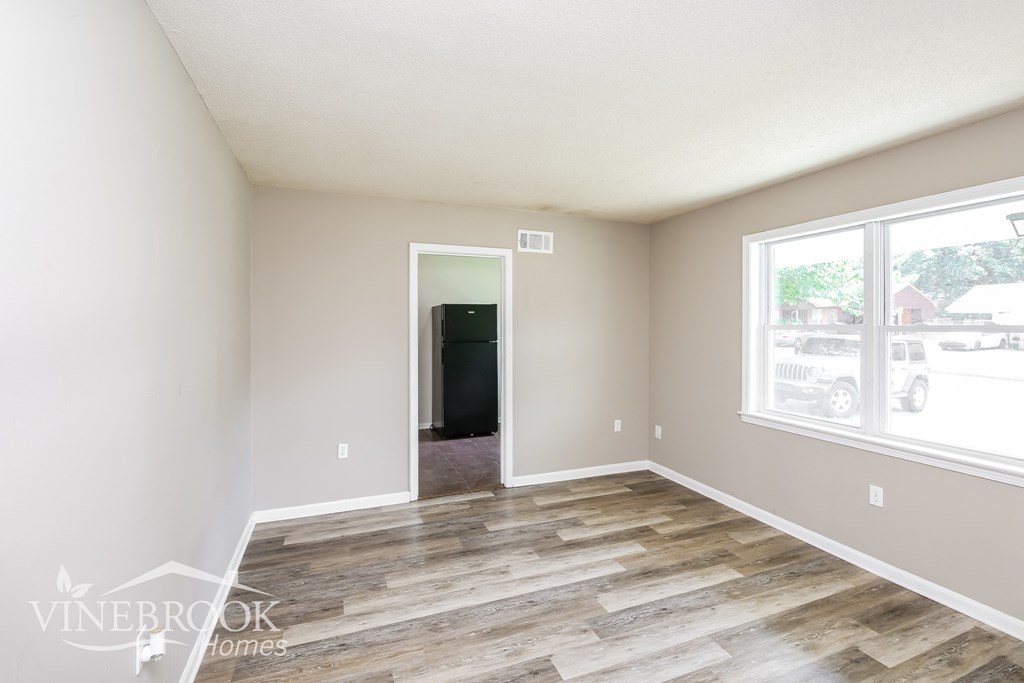 a living room with a wooden floor and a large window