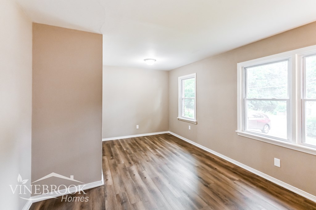 the living room of a home with wood flooring and white walls and windows