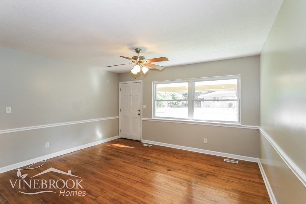 the living room of a home with wood floors and a ceiling fan
