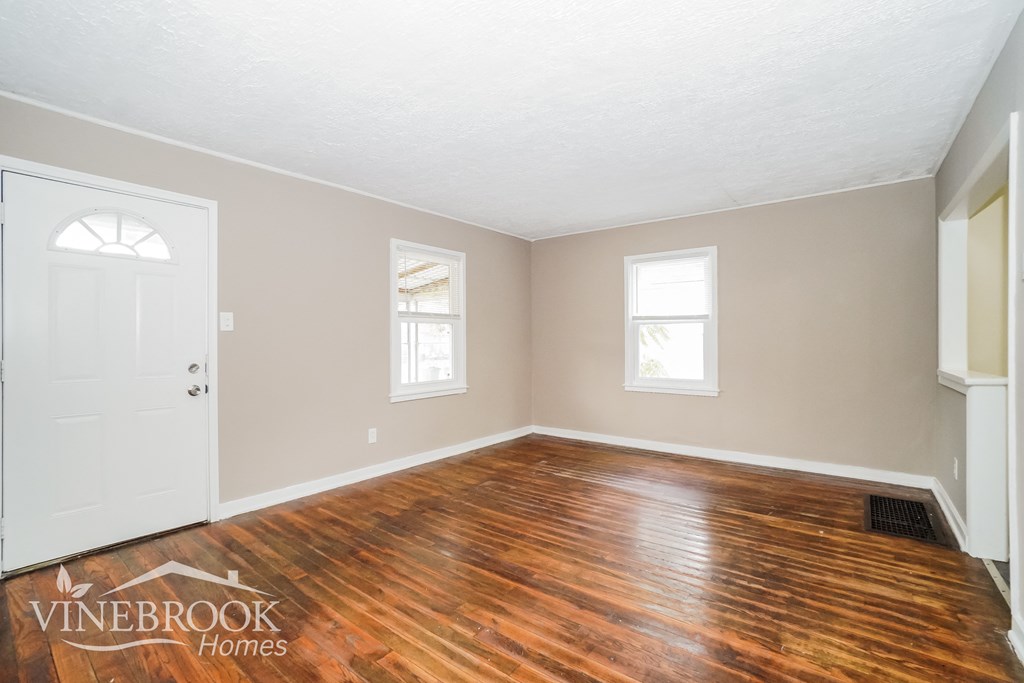 the living room of a home with wooden floors and a white door