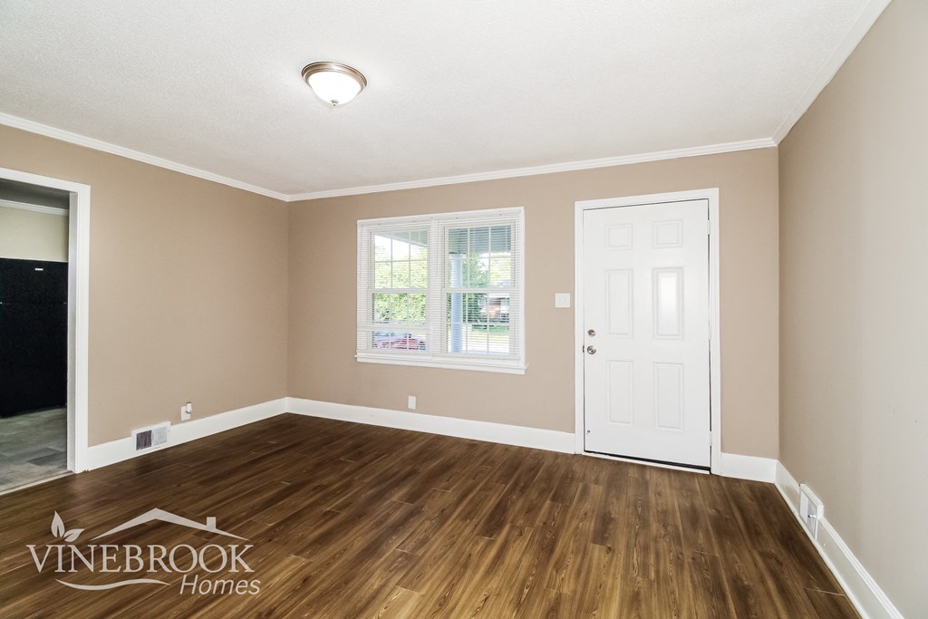 the living room of a home with wooden floors and a white door