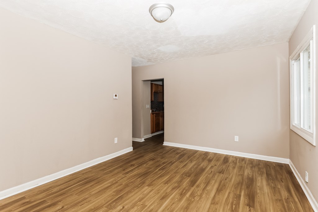 an empty living room with wood flooring and white walls