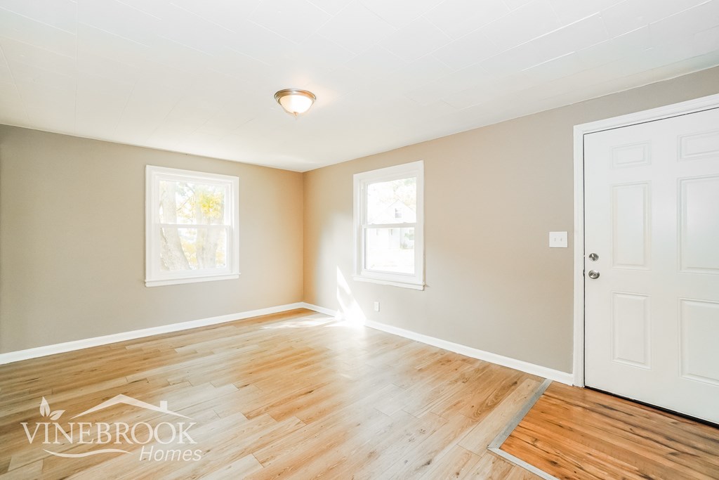 the living room of a home with wood floors and a white door